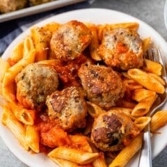 meatballs and pasta mixed together on a white plate.