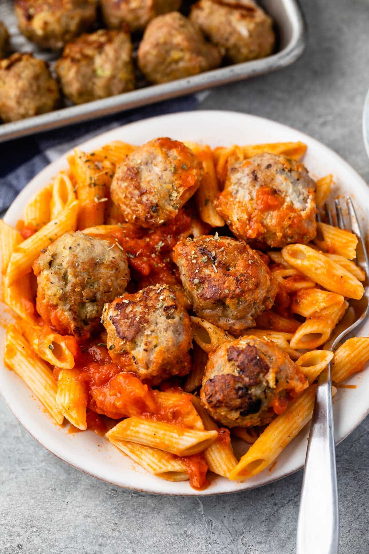 meatballs and pasta mixed together on a white plate.