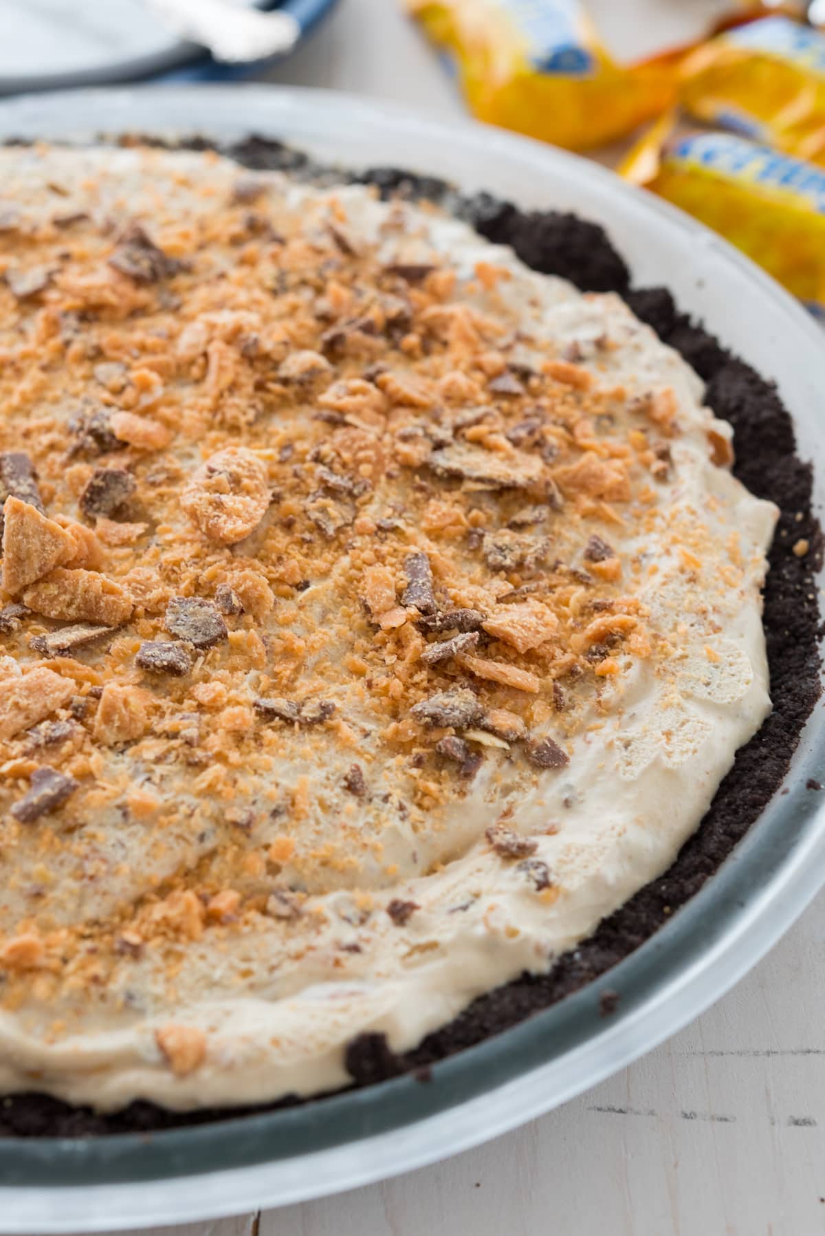 butterfinger pie on a white plate covered in chocolate sauce.