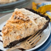 butterfinger pie on a white plate covered in chocolate sauce.