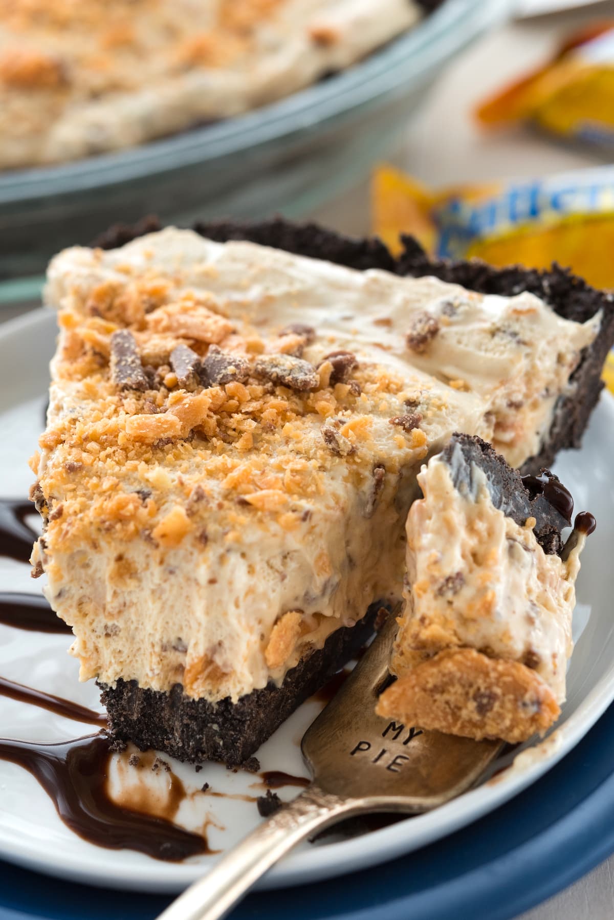 butterfinger pie on a white plate covered in chocolate sauce.