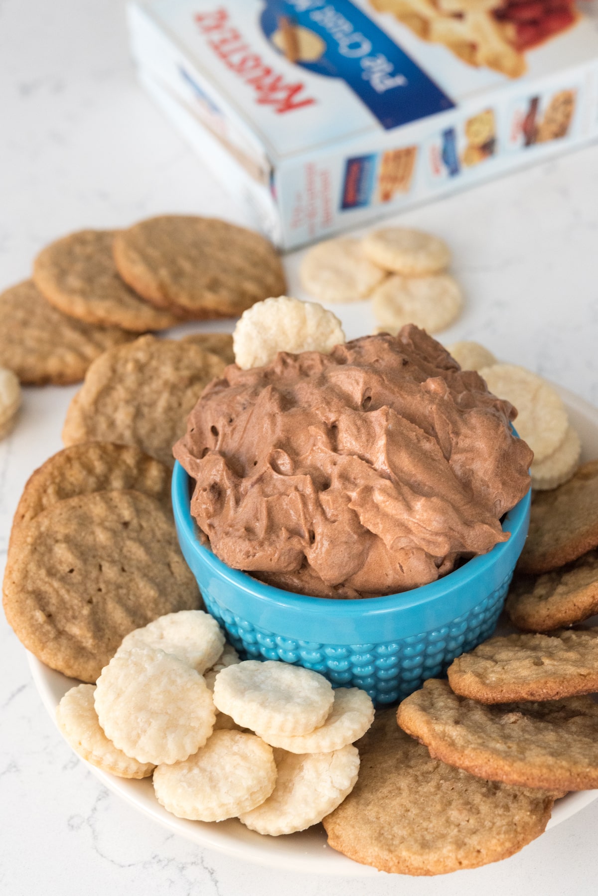chocolate dip in a small blue glass surrounded by cookies.