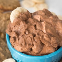 chocolate dip in a small blue glass surrounded by cookies.