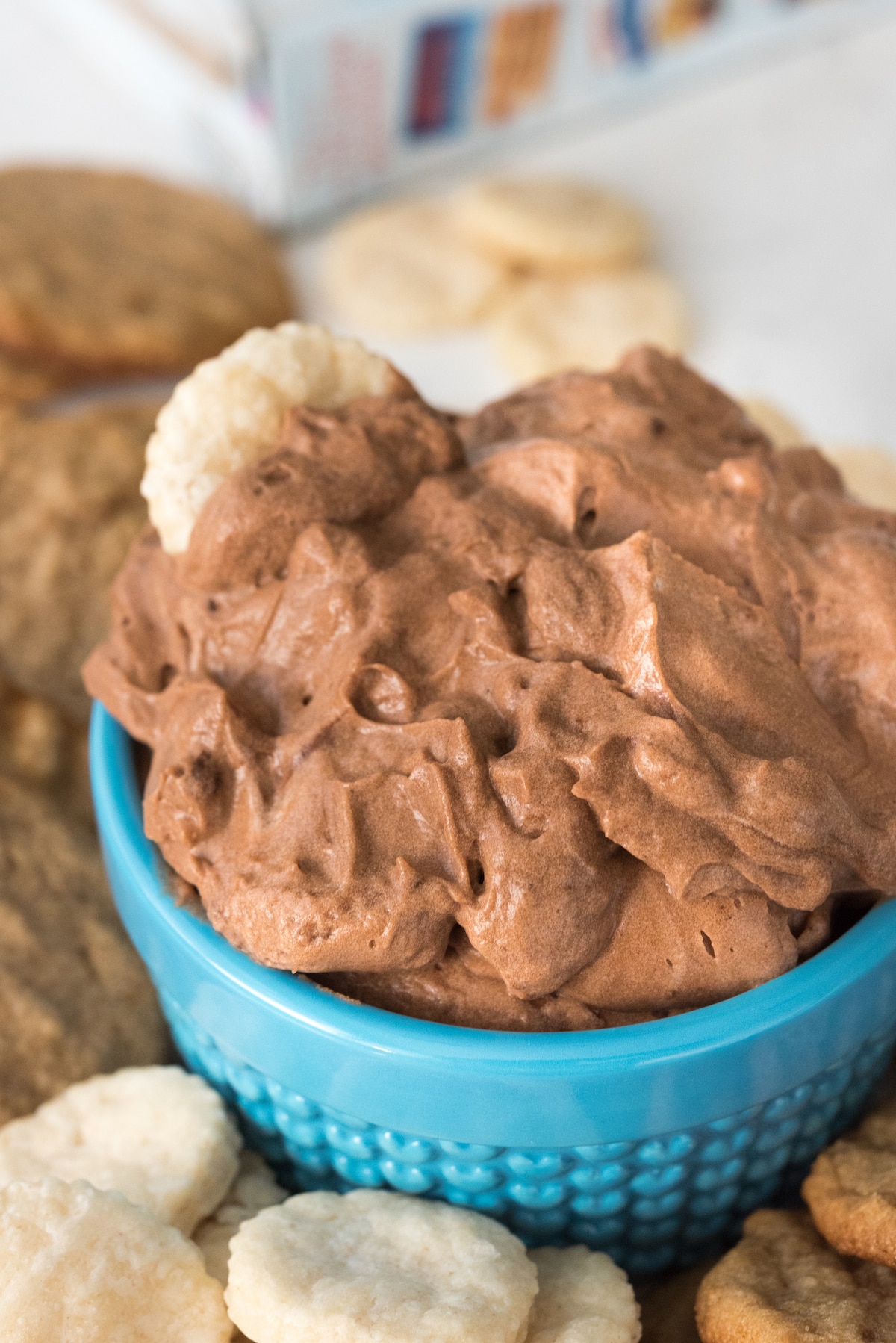 chocolate dip in a small blue glass surrounded by cookies.