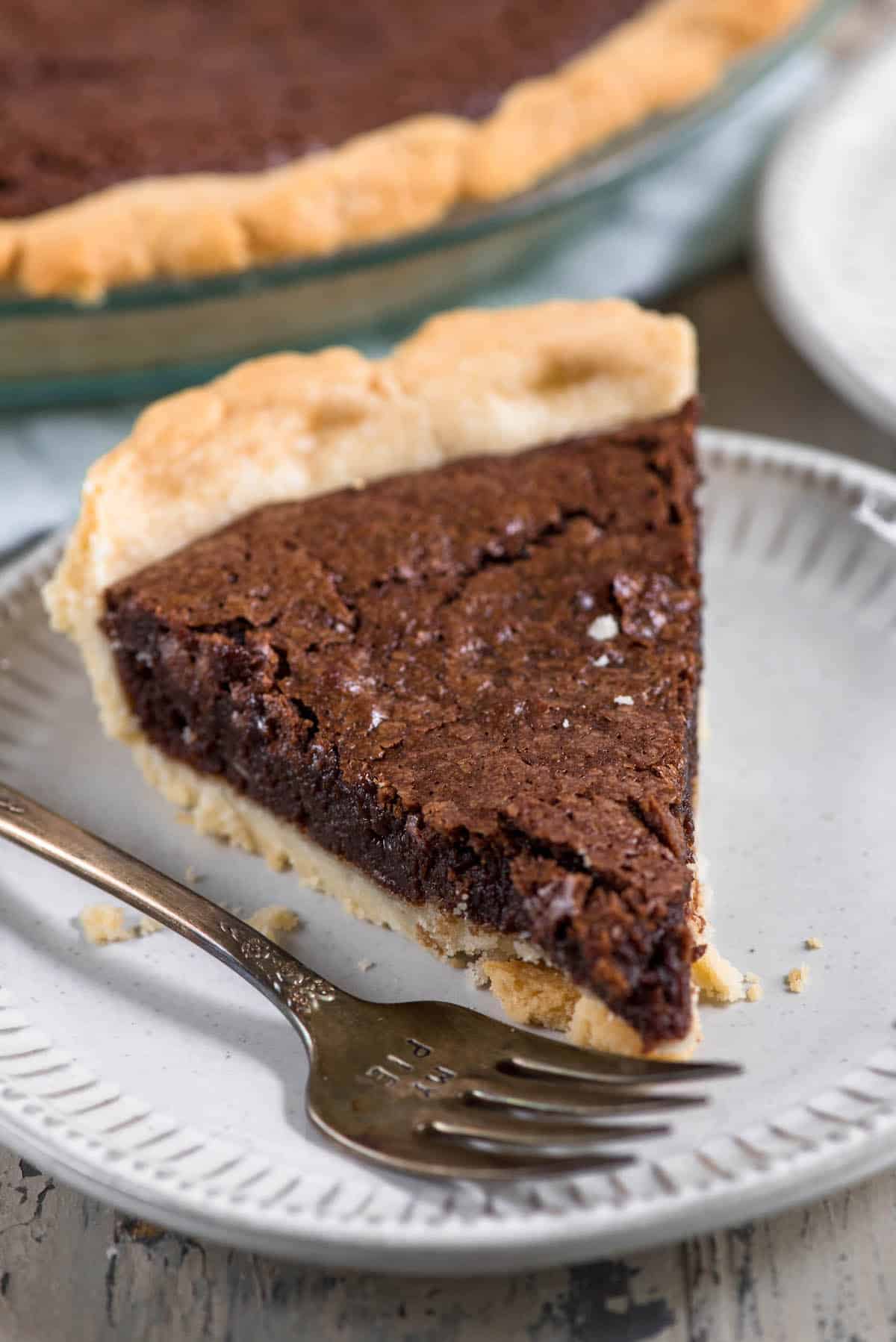 slice of fudge pie white plate with fork.