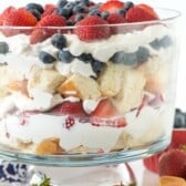 trifle mixed with strawberries and blueberries and bread in a clear jar.