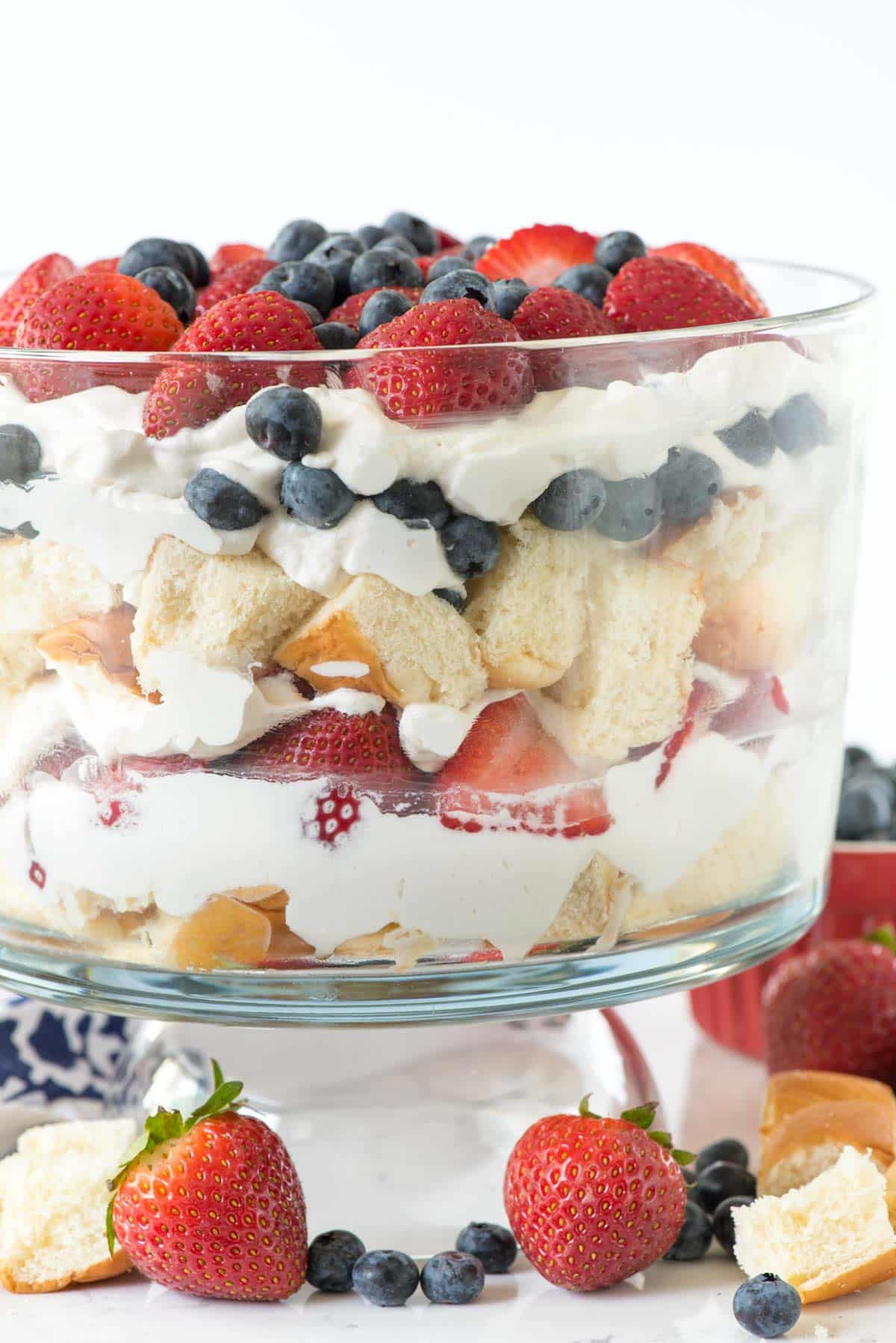 trifle mixed with strawberries and blueberries and bread in a clear jar.