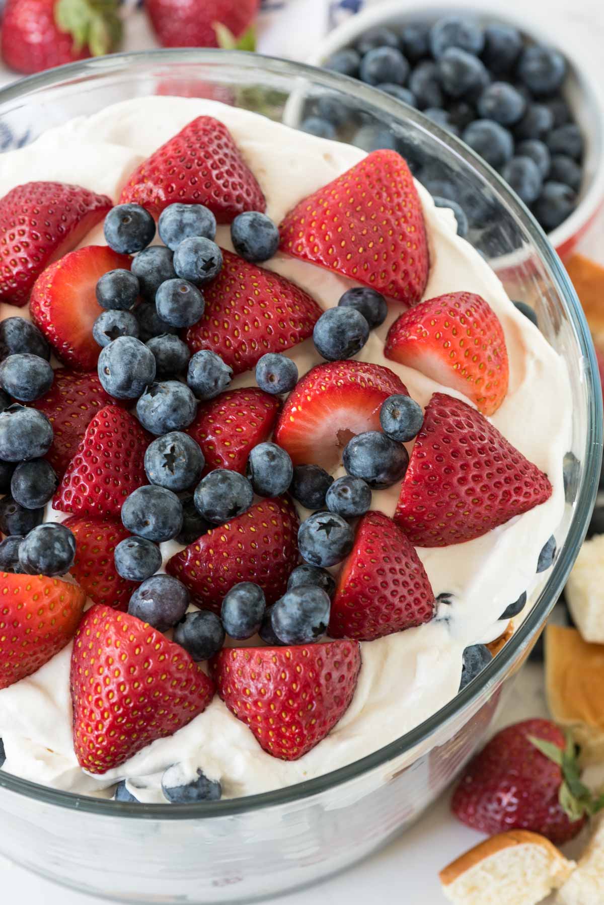 trifle mixed with strawberries and blueberries and bread in a clear jar.