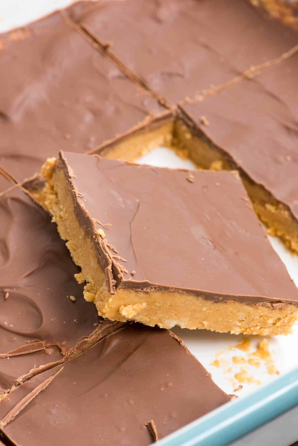 stacked peanut butter bars next to a spoonful of peanut butter.