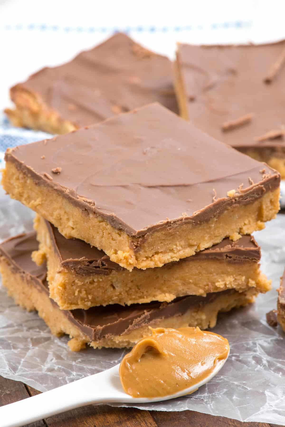 stacked peanut butter bars next to a spoonful of peanut butter.