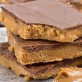 stacked peanut butter bars next to a spoonful of peanut butter.