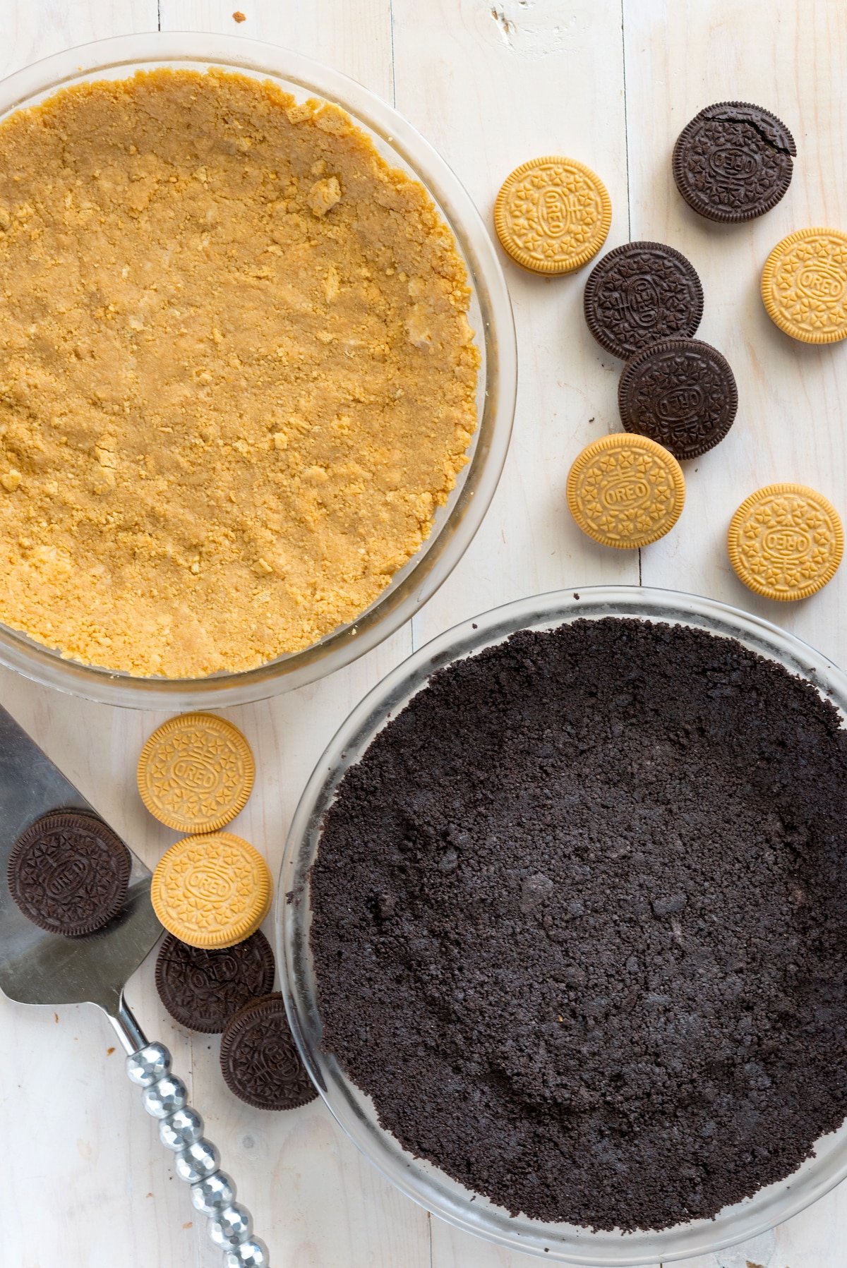 regular and golden oreos crushed into a pie crust form in clear pie pans.
