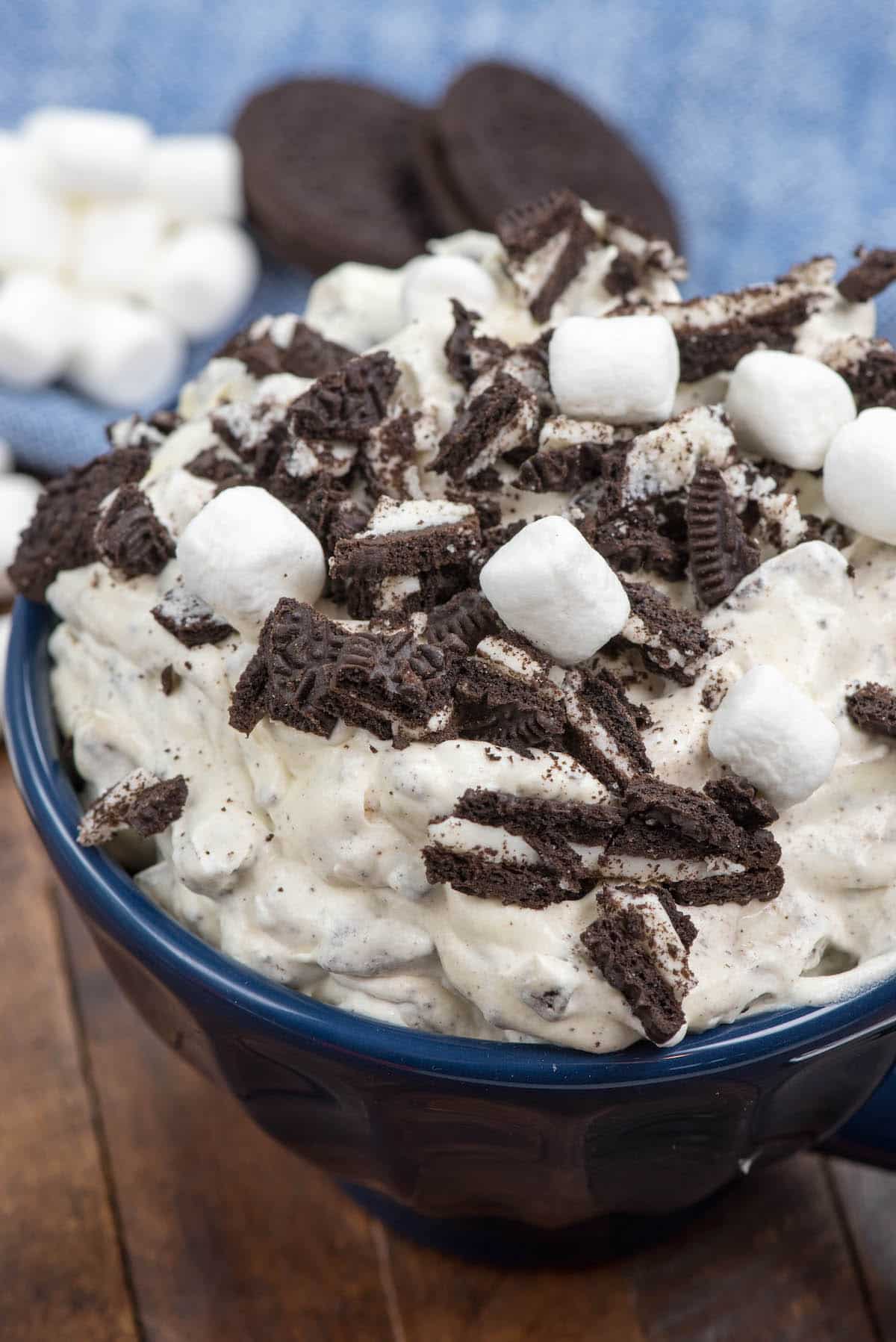 oreo fluff in a blue bowl with marshmallows and chopped oreos on top.