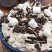 oreo fluff in a blue bowl with marshmallows and chopped oreos on top.