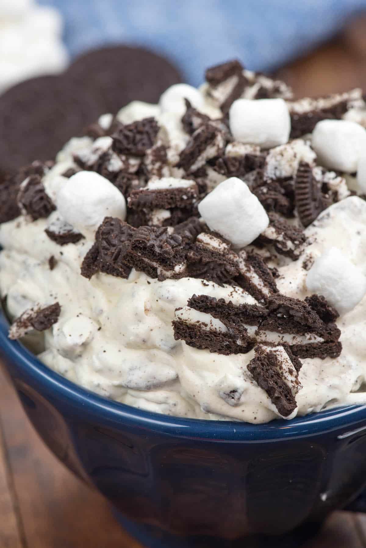 oreo fluff in a blue bowl with marshmallows and chopped oreos on top.