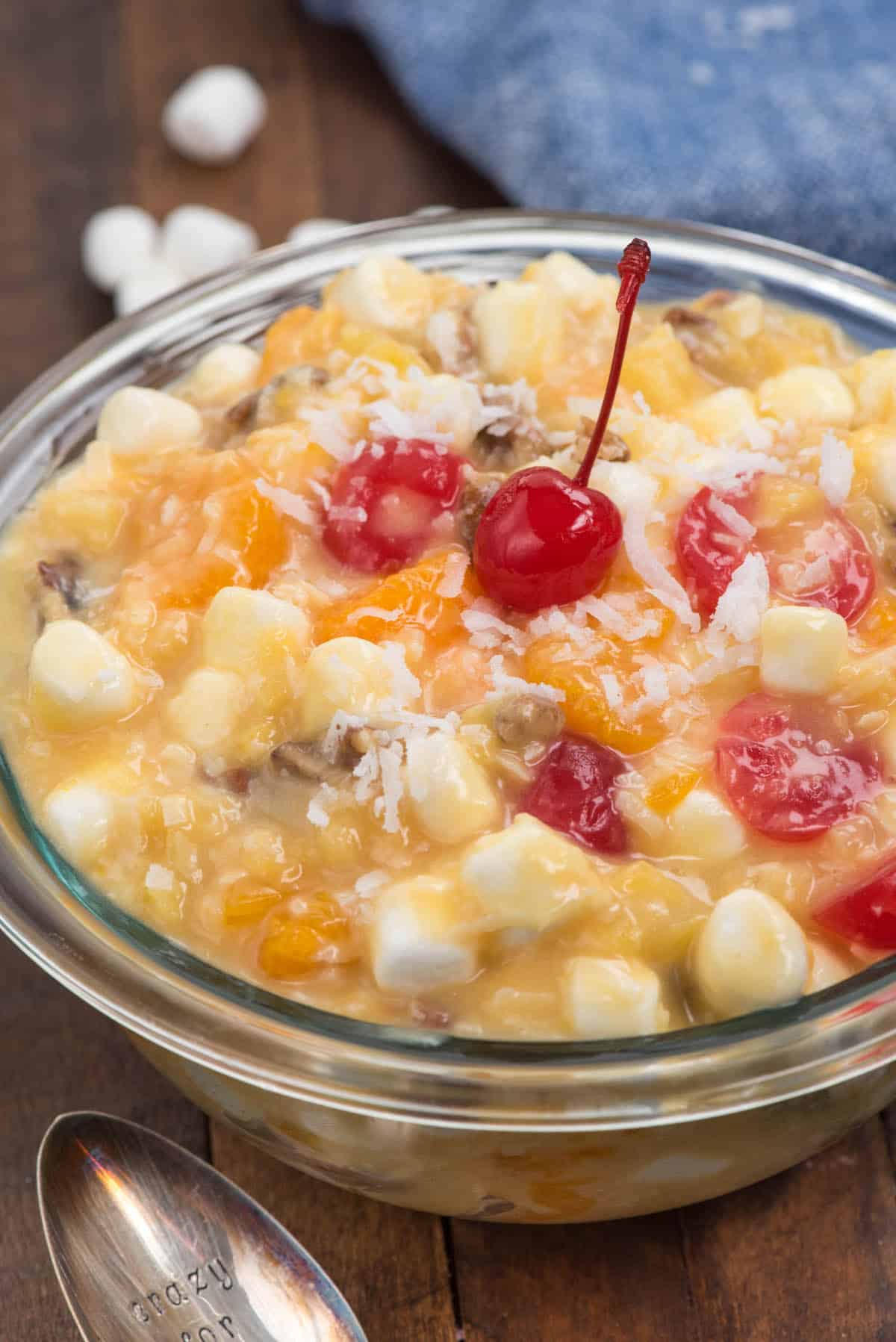 clear bowl with marshmallows and cherries and other ingredients mixed together.