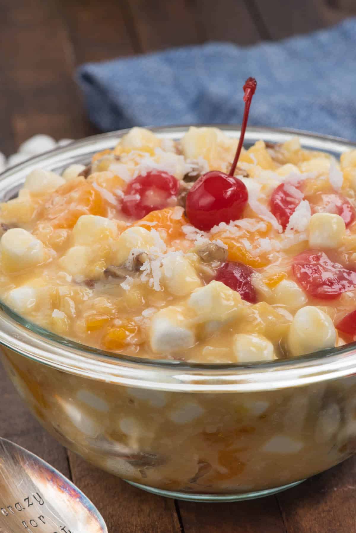 clear bowl with marshmallows and cherries and other ingredients mixed together.