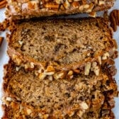 sliced banana bread topped with frosting and pecans.