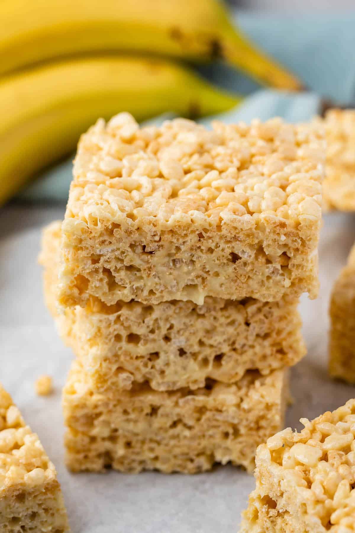 stacked Krispie treats with bananas in the back.