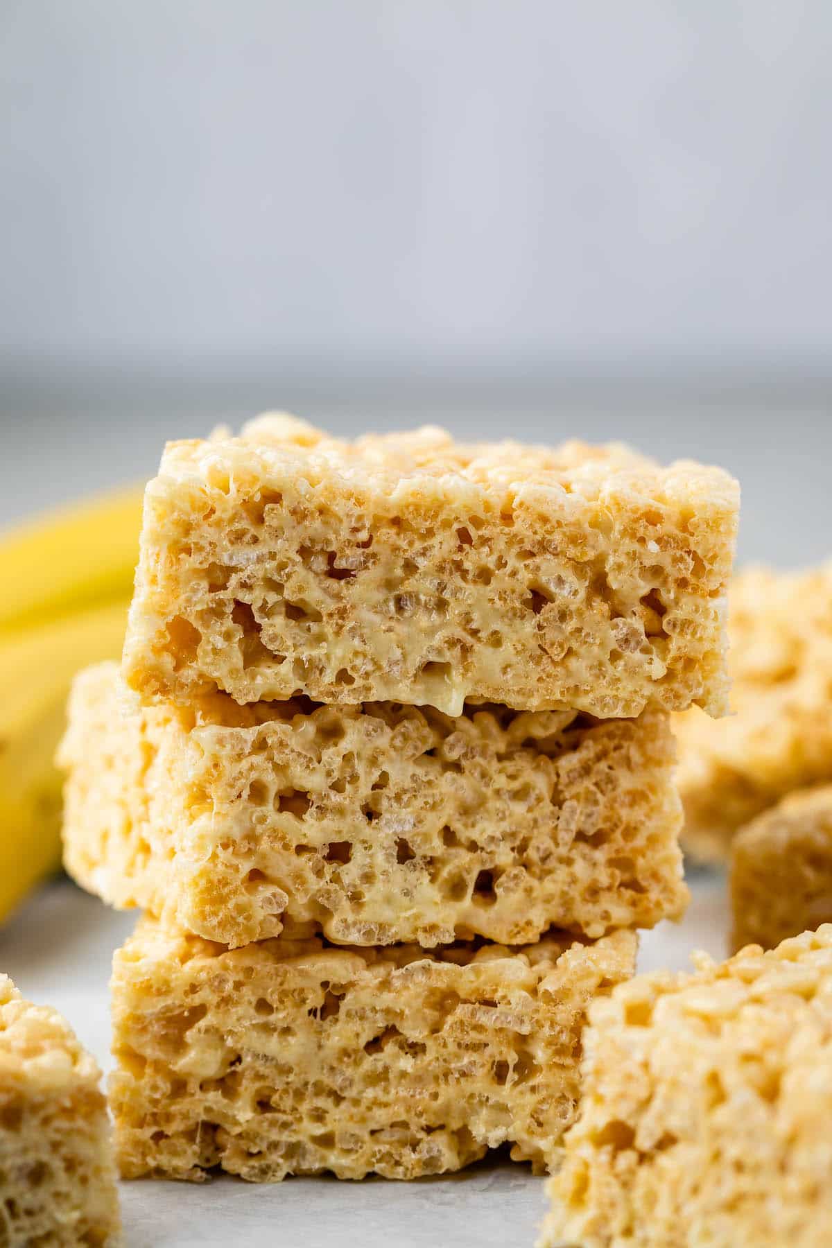 stacked Krispie treats with bananas in the back.