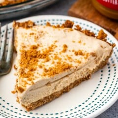 slice of pie on a white plate with biscoff crumble on top.