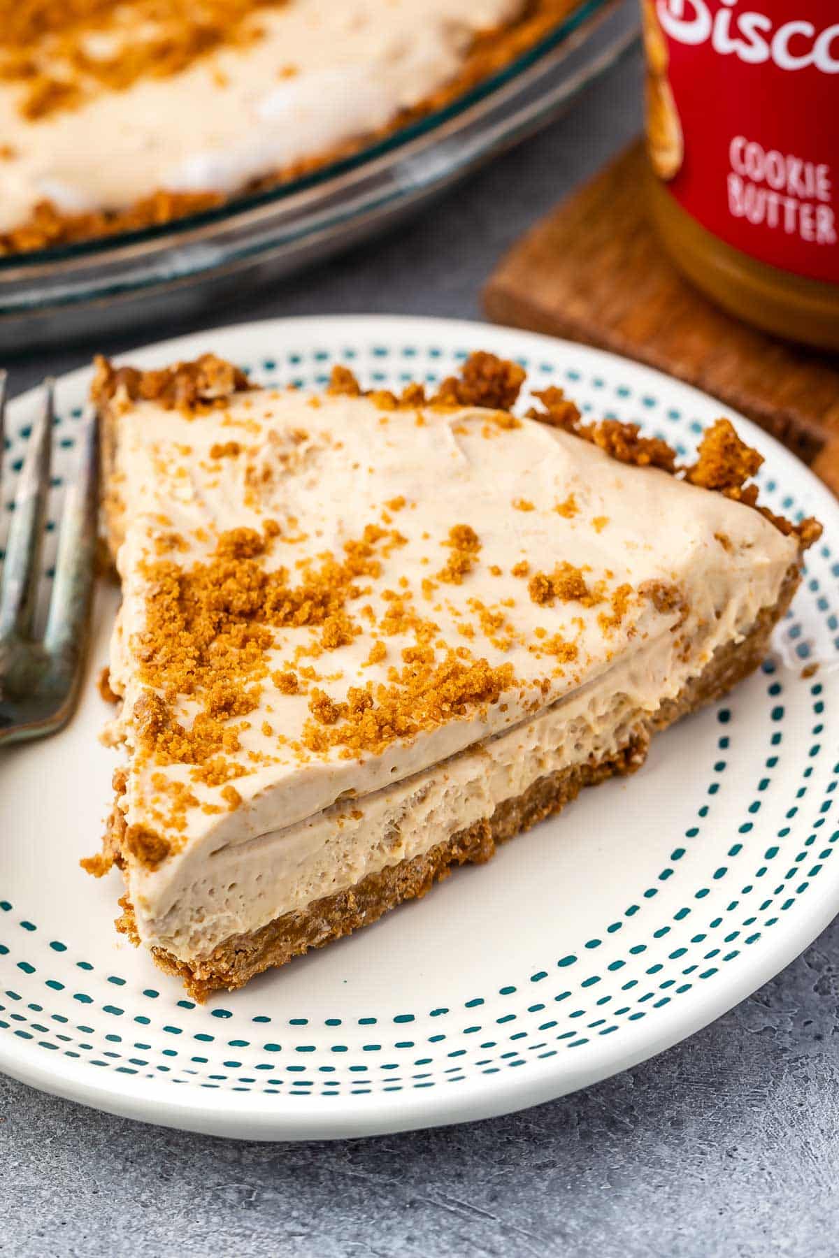 slice of pie on a white plate with biscoff crumble on top.