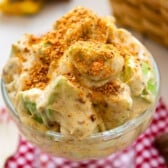 apple salad in a clear raised bowl covered with crushed butterfinger candy bar.