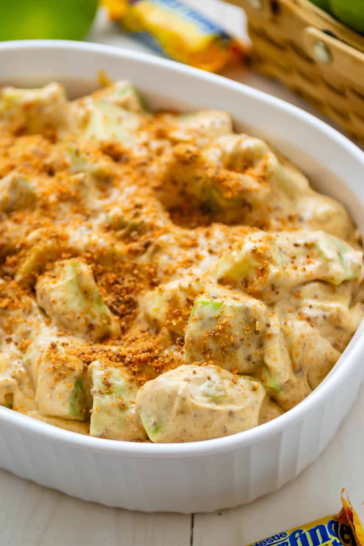 apple salad in a white container covered with crushed butterfinger candy bar.