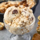 ice cream in a clear ice cream glass next to a spoonful of peanut butter.