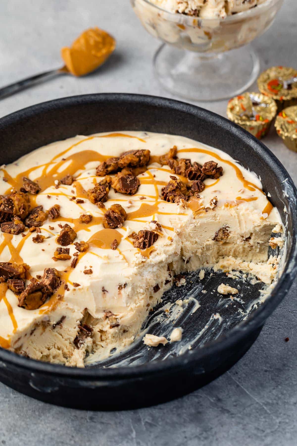 ice cream in a black skillet next to a spoonful of peanut butter.