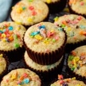 fruity pebbles muffins in a brown cupcake tin topped with fruity pebble cereal.