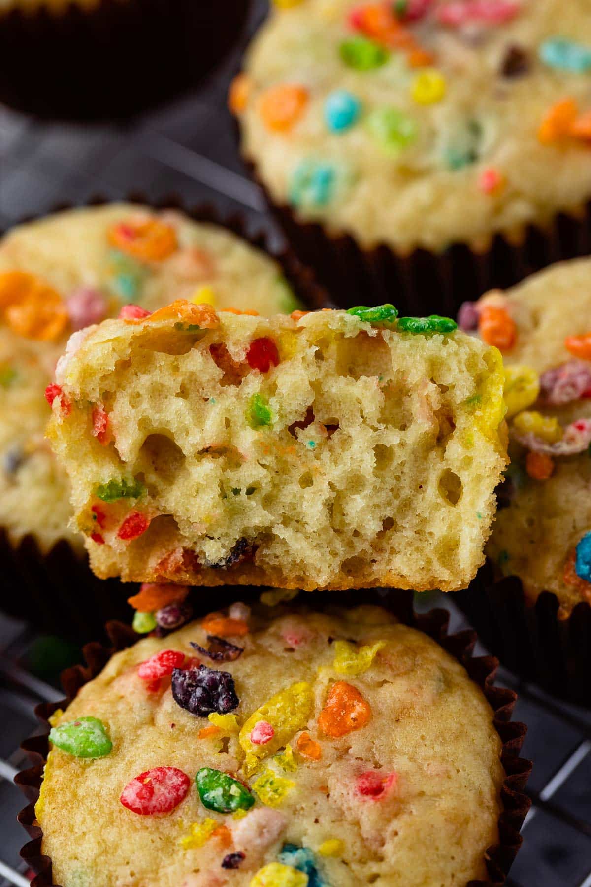 fruity pebbles muffins in a brown cupcake tin topped with fruity pebble cereal.