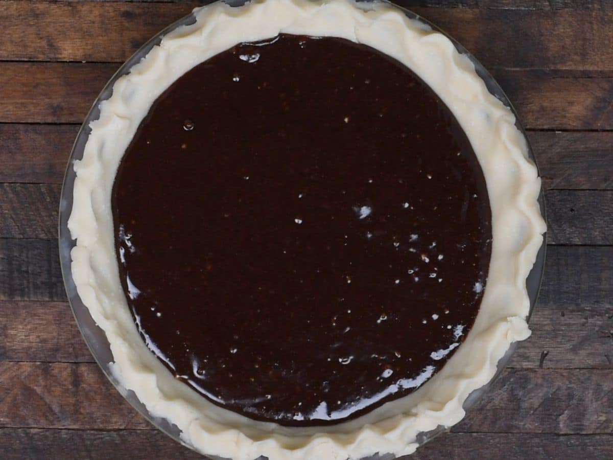 chocolate batter in pie crust on wood background.