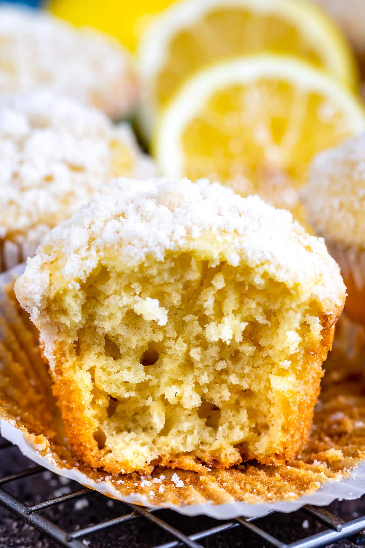 lemon muffins topped with a white crumb topping and lemons in the background.
