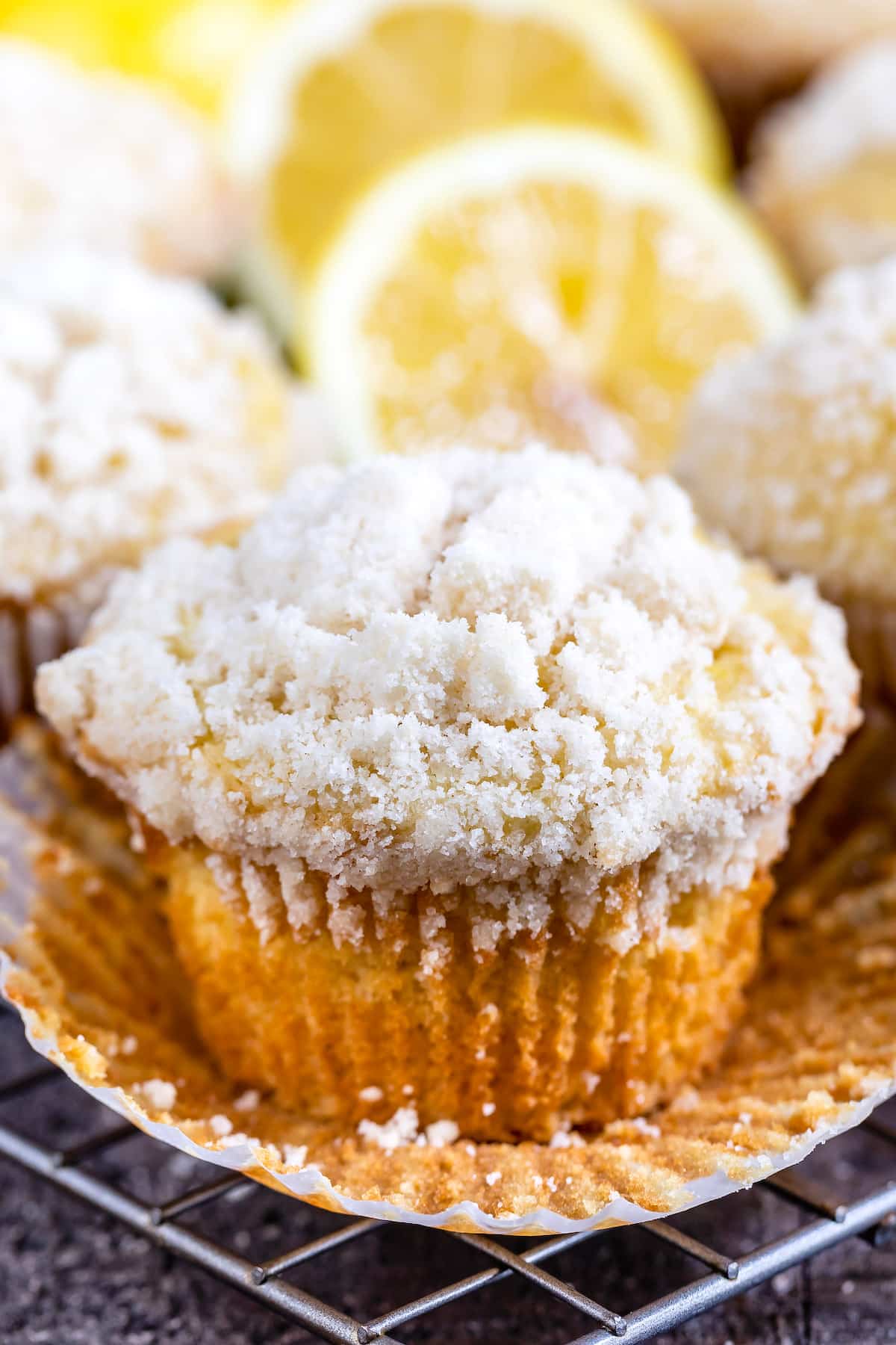 lemon muffins topped with a white crumb topping and lemons in the background.