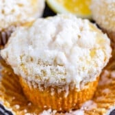 lemon muffins topped with a white crumb topping and lemons in the background.