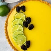 lime tart with a lime slices and blackberries on top.