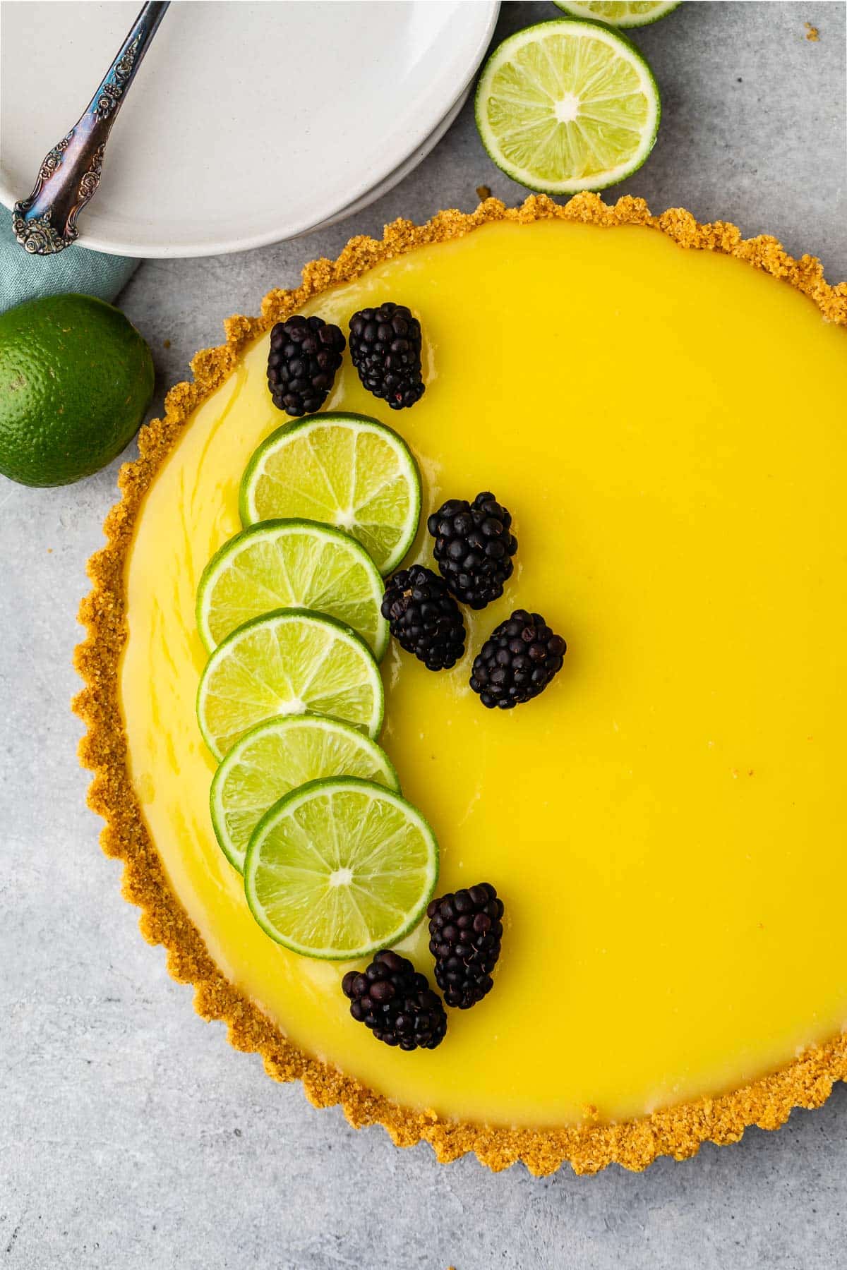 lime tart with a lime slices and blackberries on top.