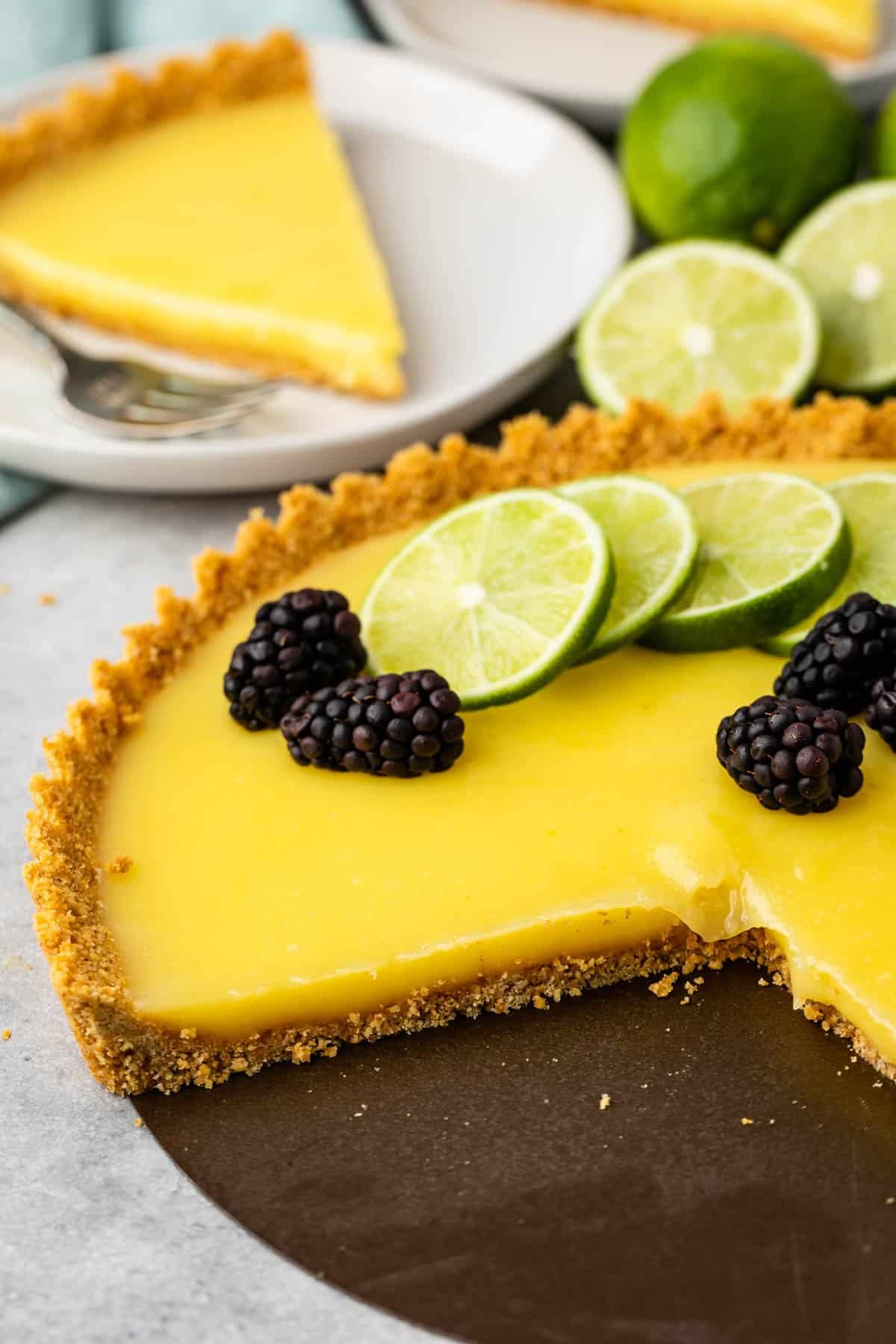 lime tart with a lime slices and blackberries on top.