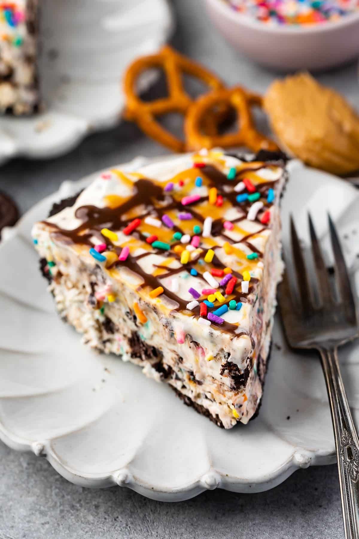 ice cream pie in a pie tin topped with chocolate and caramel sauce and sprinkles.