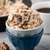 ice cream in a white and blue cup next to a spoonful of nutella.