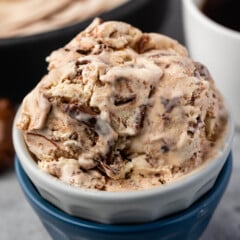 ice cream in a white and blue cup next to a spoonful of nutella.