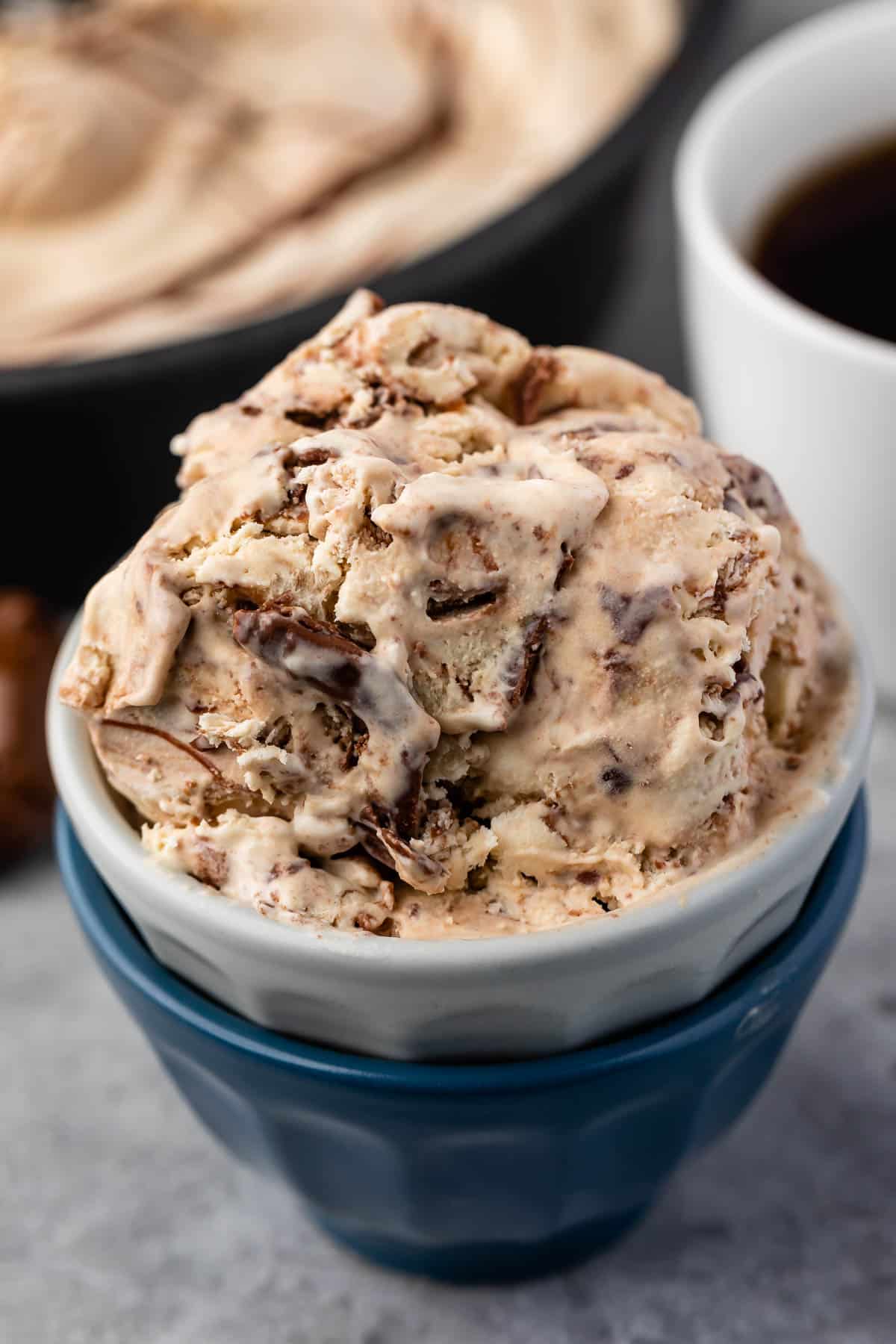 ice cream in a white and blue cup next to a spoonful of nutella.