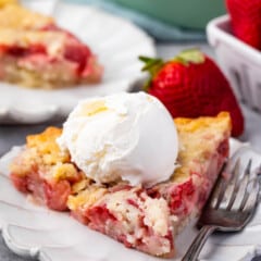 strawberry cobbler on a grey plate with ice cream on top.