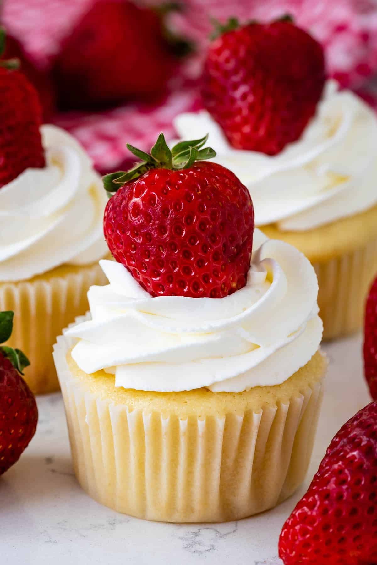 cupcakes with chopped strawberries in the center and topped with white frosting and a strawberry.
