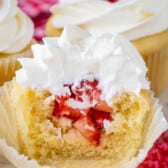cupcakes with chopped strawberries in the center and topped with white frosting.