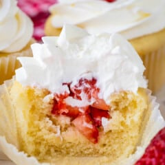 cupcakes with chopped strawberries in the center and topped with white frosting.