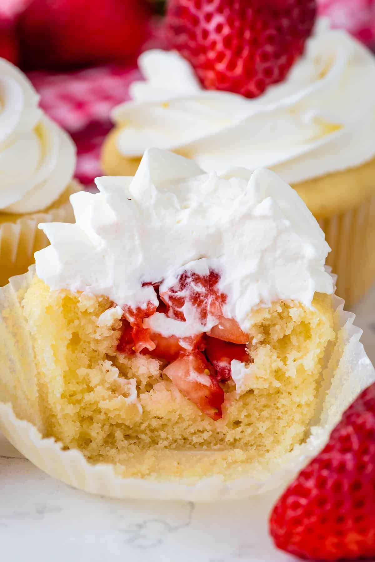 cupcakes with chopped strawberries in the center and topped with white frosting.