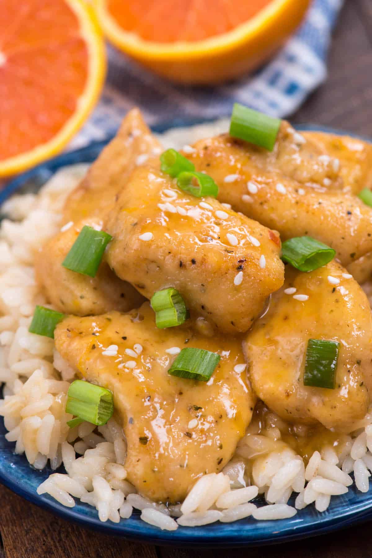 multiple pieces of orange chicken on a pile of rice on a blue plate.