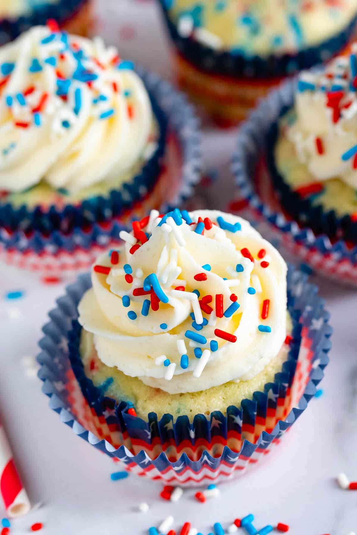 cupcakes with vanilla frosting and with red white and blue sprinkles on top.